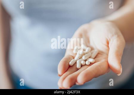 La mano di Womans sta tenendo le pillole. Sovradosaggio di capsule medicinali nel primo piano delle palme. Giornata mondiale della salute. Concetto di assistenza sanitaria. La donna prende il farmaco. Foto Stock