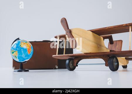 Aereo in legno, mondo globo, valigie marroni. Viaggia in tutto il mondo Foto Stock