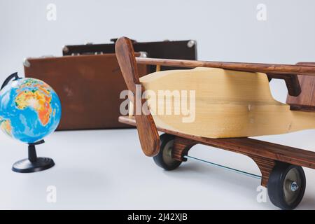 Aereo in legno, mondo globo, valigie marroni. Viaggia in tutto il mondo Foto Stock