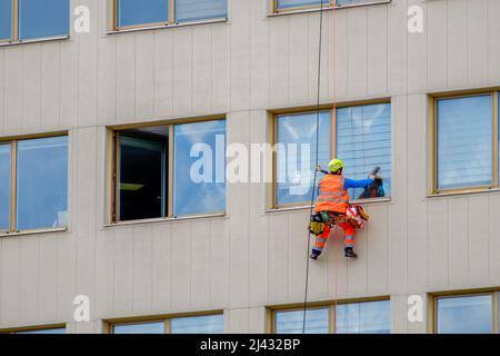 Minsk, Bielorussia - 11 aprile 2022: Il climber industriale lava le finestre sulla facciata di un edificio nel quartiere degli affari Foto Stock