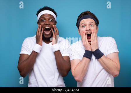 Due giovani uomini sono ecscatici che alzano le mani in faccia. Notizie positive sullo sport. Foto studio Foto Stock