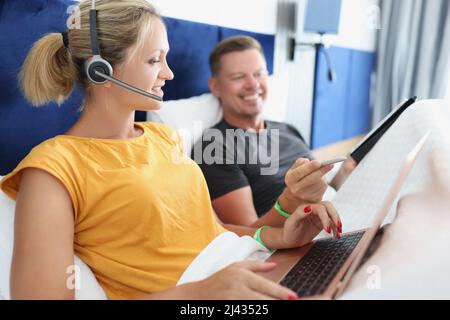 Coppia di famiglia di blogger freelance che lavorano su un notebook mentre si trovano a letto Foto Stock