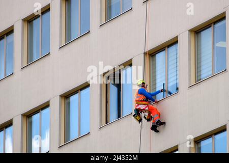 Minsk, Bielorussia - 11 aprile 2022: Il climber industriale lava le finestre sulla facciata di un edificio. Vista laterale Foto Stock