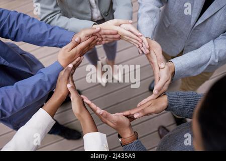 Muovendosi insieme. Colpo di un gruppo di uomini d'affari irriconoscibili che formano un cerchio con le loro mani fuori. Foto Stock