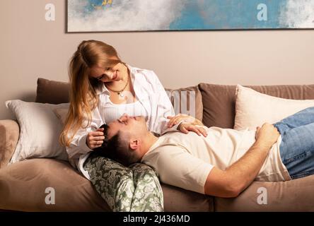 Coppia felice amore rilassarsi sul divano a casa, sedersi e sdraiarsi sul divano. Foto Stock
