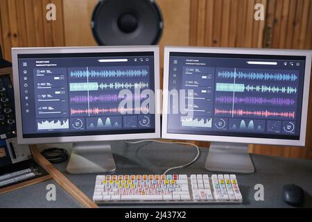 Immagine di sfondo di due schermi per computer con tracce audio in studio di registrazione domestico, concetto di produzione musicale Foto Stock
