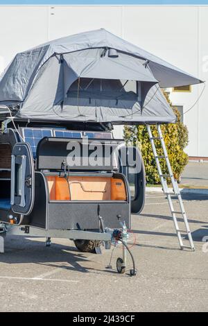 Casa di rimorchio con un pannello solare e una tenda pieghevole con posti letto sul tetto. Foto Stock