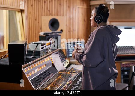 Vista laterale ritratto di femmina produttore di musica mostrando pollice in su mentre supporta band in studio di registrazione, spazio copia Foto Stock