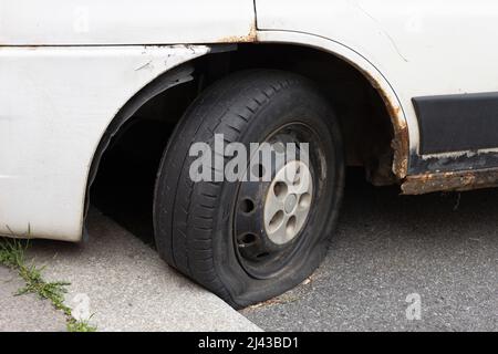 Praga, Repubblica Ceca, Czechia - 7 aprile 2022: Pneumatico e pneumatico sgonfio - ruota danneggiata e danneggiata su vecchia auto arrugginita. Messa a fuoco superficiale. Foto Stock