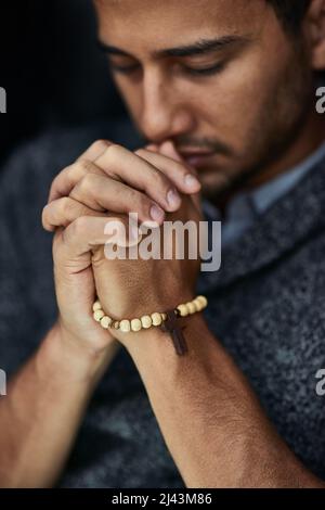 Pregare per un miracolo. Primo piano di un giovane che prega con gli occhi chiusi. Foto Stock