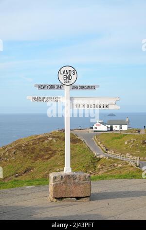 Il famoso cartello di Land's End con la prima e ultima casa in lontananza in Cornovaglia Inghilterra Regno Unito Foto Stock