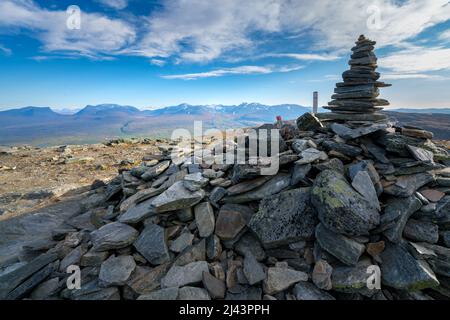 Tumulo di pietra sulla cima di Nuolja, o Njulla, montagna nel Parco Nazionale di Abisko, in Svezia artica. Porta Lapponiana, o Lapporten, nella parte posteriore. Avventura in Foto Stock