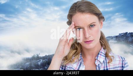 Immagine composita della donna caucasica stressata contro il cielo blu sul paesaggio invernale Foto Stock