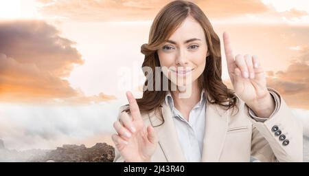 Immagine composita di donna d'affari caucasica che tocca uno schermo invisibile contro il cielo del tramonto Foto Stock