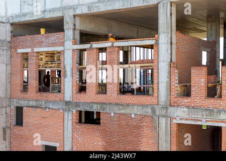 muratura delle pareti esterne di una struttura monolitica a telaio, formazione di aperture per finestre con posa di travi in calcestruzzo, fuoco selettivo Foto Stock