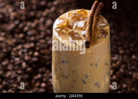 Caffè latte ghiacciato. Tazza di caffè latte ghiacciato, tè al latte su sfondo di semi di caffè scuri Foto Stock