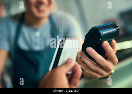 Metterlo sulla mia carta. Scatto ritagliato di un barista irriconoscibile che prende un pagamento con carta di credito. Foto Stock