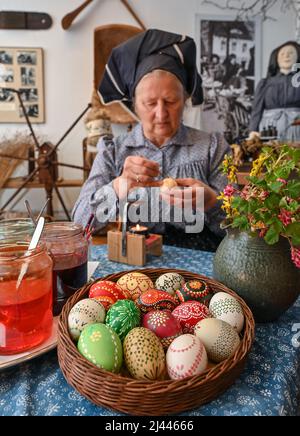 Dissen, Germania. 05th Apr 2022. Babette Zenker, direttore del Lower Sorbian Museum of Local History di Dissen, indossa un costume da lavoro Sorbian-Wendish e decora le uova di Pasqua utilizzando la tecnica del batik della cera. (A dpa con quill e cera: Pittura dell'uovo di Pasqua in Sorbia) Credit: Patrick Pleul/dpa/Alamy Live News Foto Stock