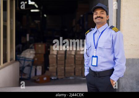 Ritratto di una guardia di sicurezza maschile con le mani in tasca durante il lavoro in magazzino Foto Stock