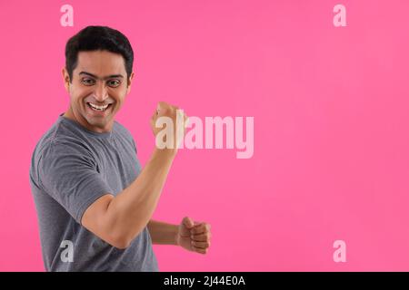 Ritratto di un giovane felice che rallegrava alzando il pugno Foto Stock
