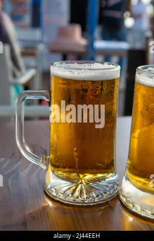 Due bicchieri da pinta con birra fredda serviti all'aperto al tramonto Foto Stock