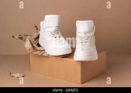 Scarpe ecologiche in pelle. Un paio di sneaker beige su sfondo marrone. Stile minimalista. Stile di vita sportivo informale. Foto Stock