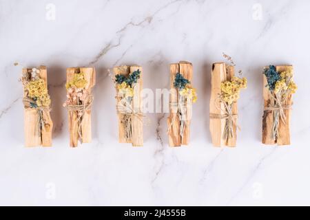 Bastoni Palo santo con mazzi di fiori secchi su sfondo di tavolo in marmo bianco. Bastoni di legno Santo per la meditazione e le pratiche spirituali. Esoterico c Foto Stock