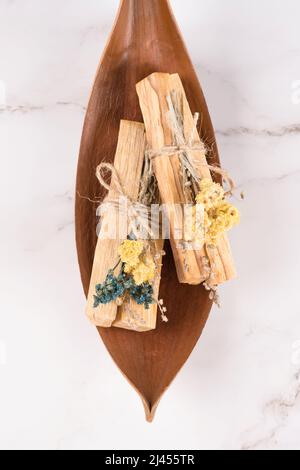 Immagine verticale dei bastoni di palo santo con mazzi di fiori secchi su sfondo di tavolo di marmo bianco. Composizione piatta con bastoncini di legno santo per me Foto Stock