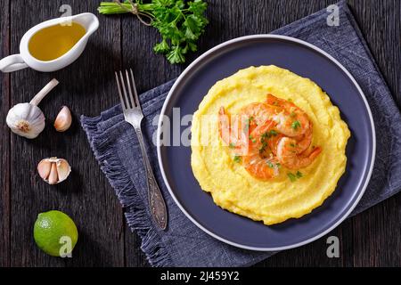 Polenta e schie fritte, piatto veneziano, polenta con gamberetti fritti su un piatto su tavola di legno scuro con aglio e salsa sullo sfondo, vista orizzontale f Foto Stock