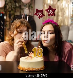 Ritratto di ragazza guardando torta di compleanno circondato da amici a festa. Foto Stock