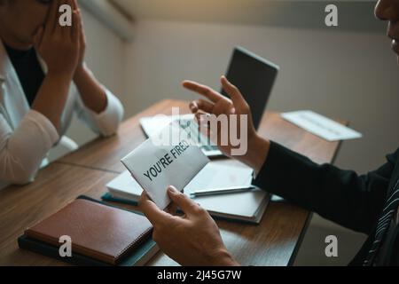 Il manager maschile sta parlando o spiegando di dover licenziare il dipendente mentre viene consegnata una busta di dimissioni al dipendente. Foto Stock