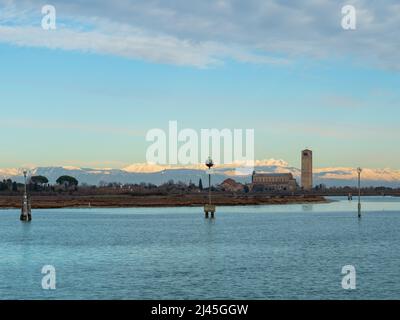 Vista da Burano verso l'isola di Torcello e la chiesa di Santa Maria Assunta con le montagne dolomitiche innevate - Italia Foto Stock