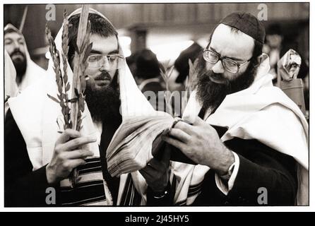 Due uomini ebrei ortodossi condividono un libro di preghiera ai servizi di Sukkos nel 1983 a Crown Heights, Brooklyn, New York. Foto Stock