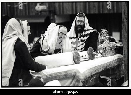 Durante i servizi mattutini di Sukkos, un ebreo ortodosso, probabilmente un rabbino, legge dalla Torah. Sede centrale di Lubavitch a Crown Heights, Brooklyn, New York City 1983. Foto Stock