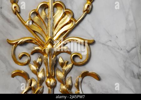 Antico frammento di decorazione d'oro d'epoca, scultura in legno su muro di marmo grigio, foto da vicino Foto Stock