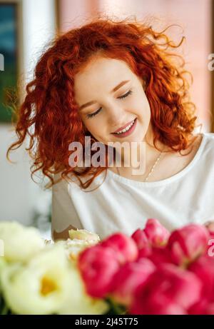 Ritratto di una giovane ragazza dai capelli rossi con un bouquet di peonie. Hobby. Floristica Foto Stock