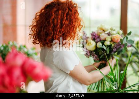 Fiorista esclusivo nel processo di creazione di un bouquet di fiori. Foto Stock