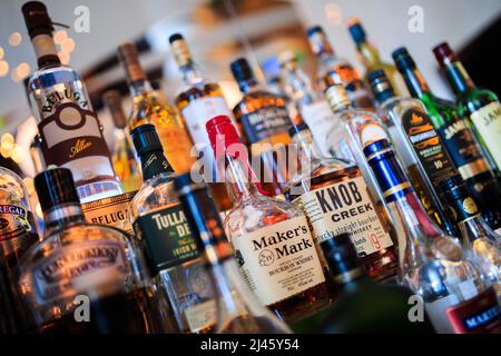 Varie bottiglie di bevande alcoliche sul ripiano del bar Foto Stock
