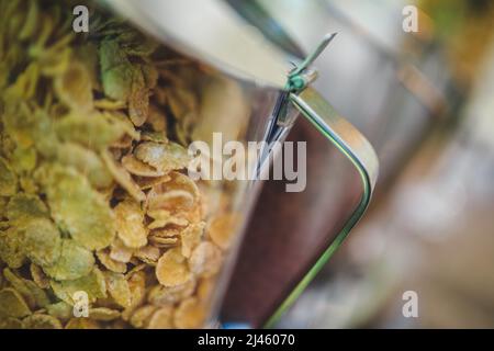 Vaso in vetro con fiocchi di mais. Il contenitore dietro i fiocchi di mais  si stende su una superficie nera. Sfondo nero. Shot verticale Foto stock -  Alamy