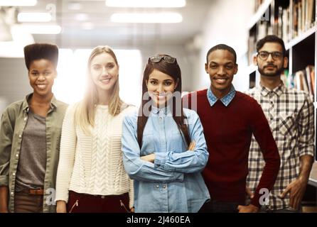 Le nostre carriere di successo iniziano con una buona formazione. Ritratto di un gruppo di studenti universitari in piedi insieme nella biblioteca del campus. Foto Stock