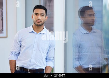 Ho grandi progetti per questo business. Scatto di un bel giovane uomo d'affari in piedi da solo in ufficio durante il giorno. Foto Stock