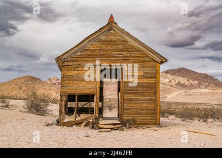 Vecchia casa abbandonata nel mezzo del deserto del Nevada con montagne sullo sfondo Foto Stock