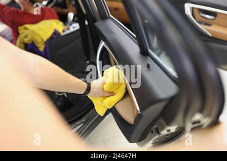 Pulitore per auto che pulisce il pannello della portiera dell'auto con un panno in microfibra Foto Stock