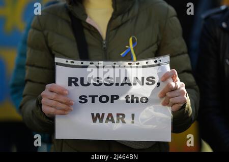 Dettagli con le mani di una donna Ucraina in possesso di una bandiera anti-guerra, pro Ucraina e anti Russia durante una protesta anti-guerra a Bucarest, Romania. Foto Stock