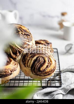 Primi piani rotoli di cannella su rastrelliera con tovagliolo e fiori bianchi in primo piano. Composizione mattina di festa. Orientamento verticale Foto Stock