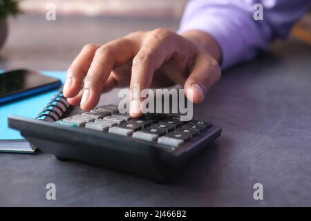 Primo piano della mano dell'uomo utilizzando la calcolatrice Foto Stock