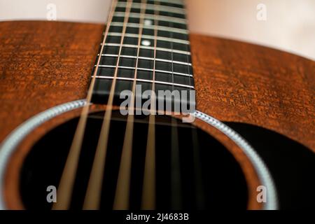 Primo piano, ripresa dall'angolo basso di una chitarra marrone scuro che guarda verso il collo Foto Stock