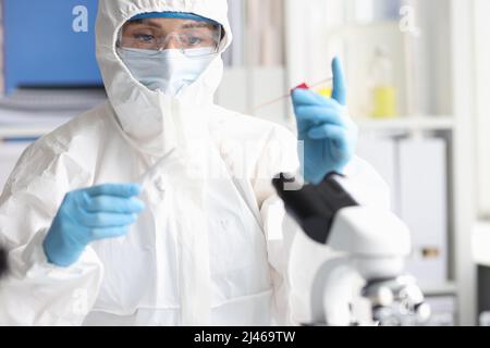 Scienziato in tuta protettiva e occhiali di protezione conduce la ricerca in laboratorio Foto Stock