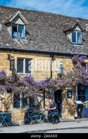 Un biker in pelle seduto fuori da un negozio di hamburger nella graziosa cittadina di Cotswold di Broadway nel Worcestershire. Foto Stock