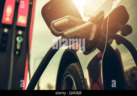 Auto elettrica moderna collegata alla stazione EV ad alta tensione durante il tempo di carica. Tema industria automobilistica. Foto Stock